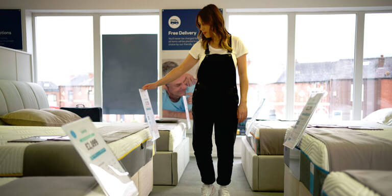 Woman viewing beds displayed at the the Land of Beds showroom