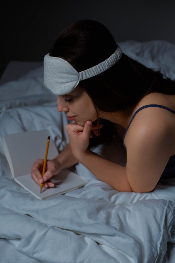 Woman ready for bed writing in her worry journal so she can beat insomnia