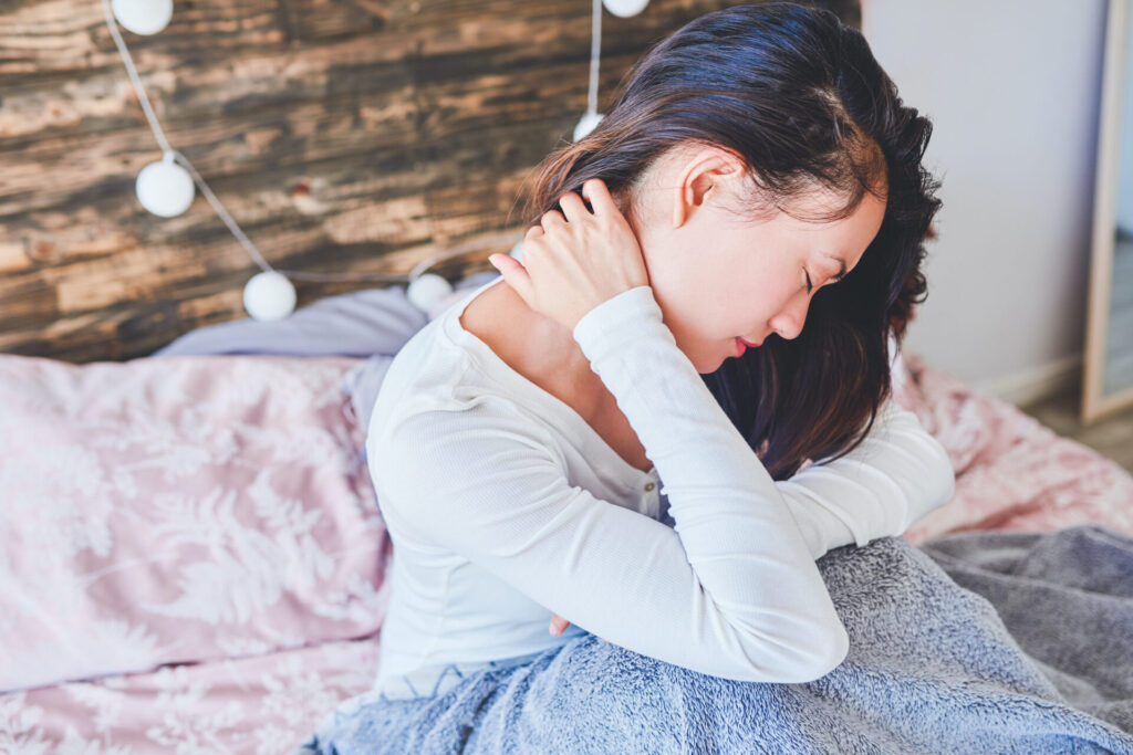 Lady struggling to sleep - holding her neck in pain. 
