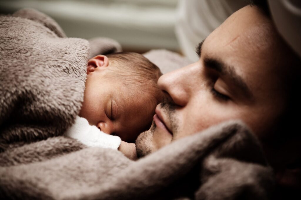 Parent sleeping soundly with his new-born baby