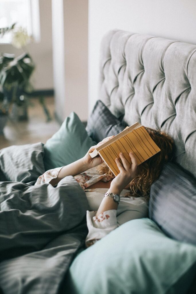Woman in bed holding a book too close to her face to be practical for reading