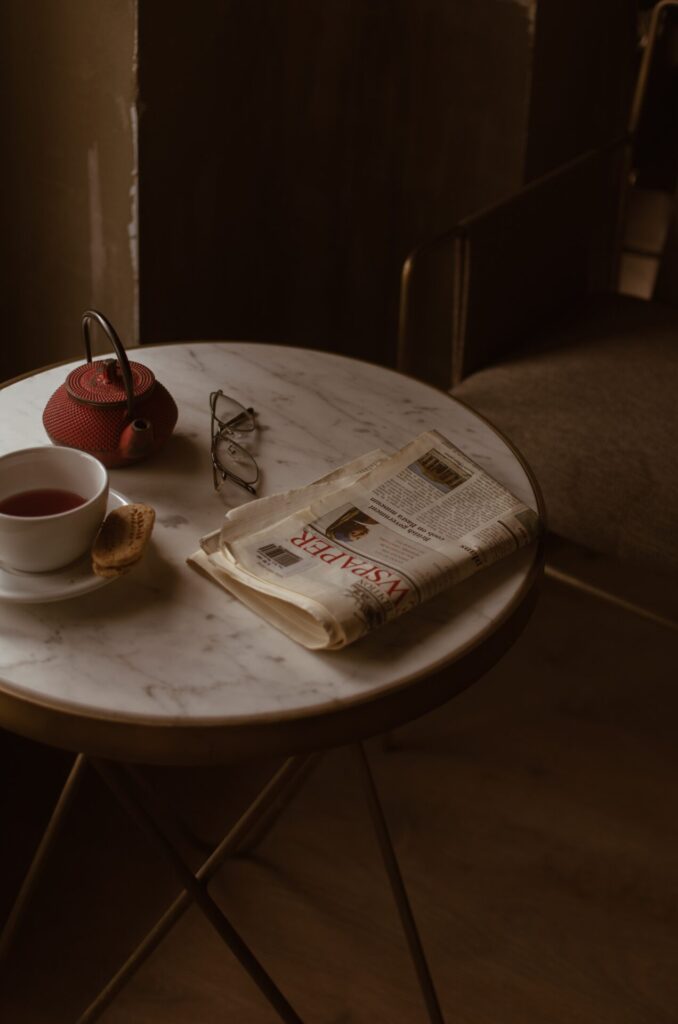 Morning breakfast routine as depicted by a newspaper and a pot of tea on a table