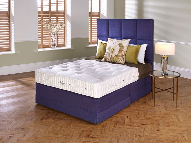 A purple bed base with a naked mattress on it