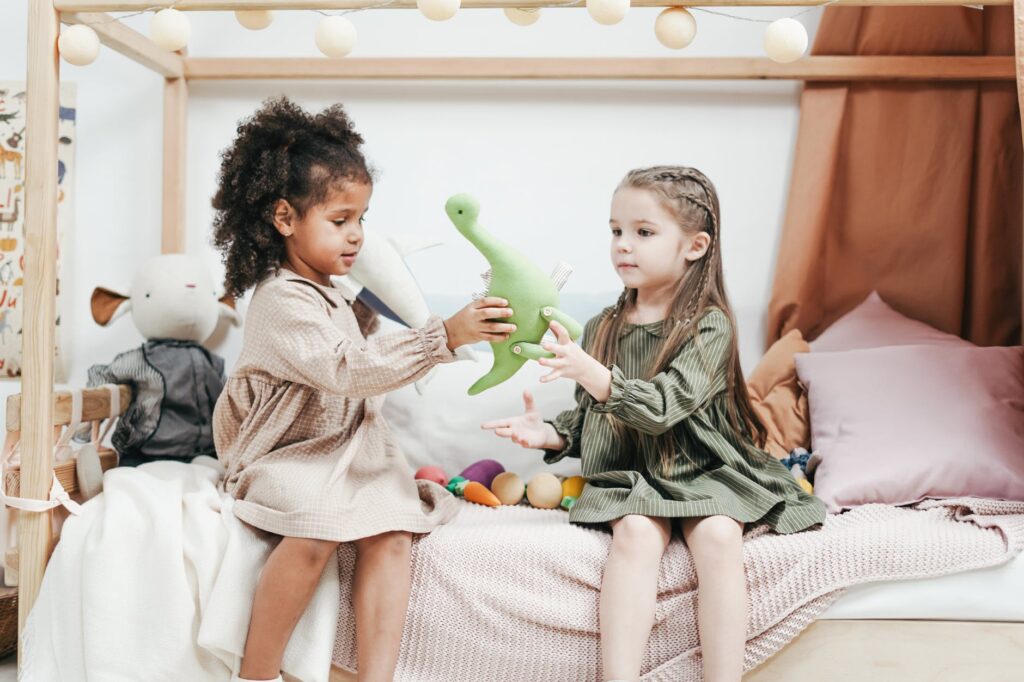 Young girls playing with a plush dinosaur