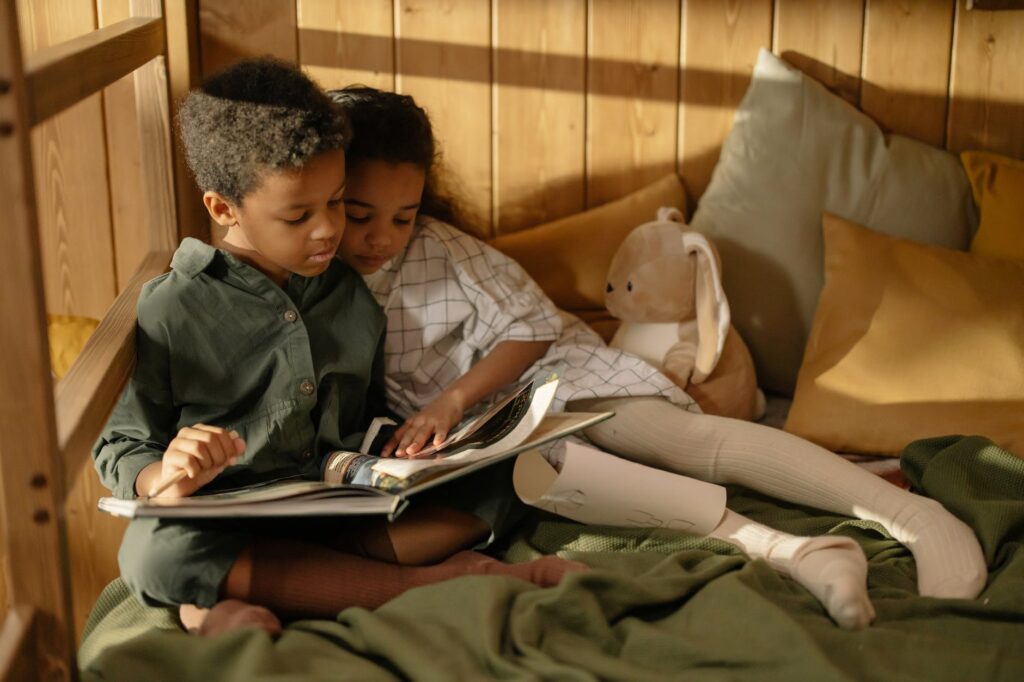 Kids reading a book on the bottom mattress of bunk beds