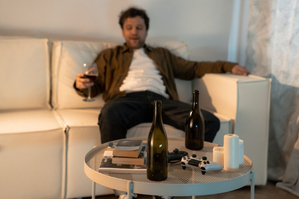 Man sat on a couch drinking wine which means he'll struggle to beat insomnia