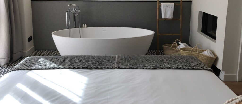 A White Bath Tub At The End Of A Bed
