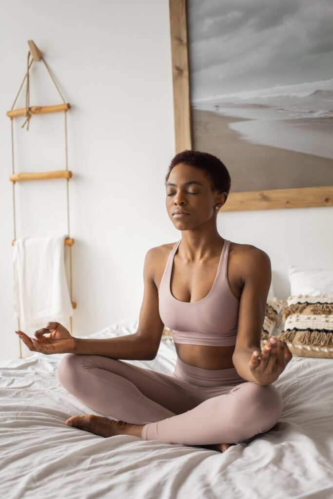 Woman meditating on her bed to encourage a quicker sleep