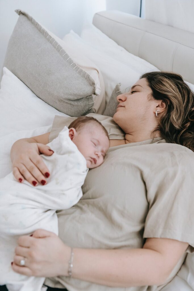 Young parent sleeping with her baby
