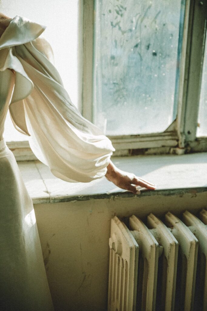 Woman fondles a window sill above a radiator