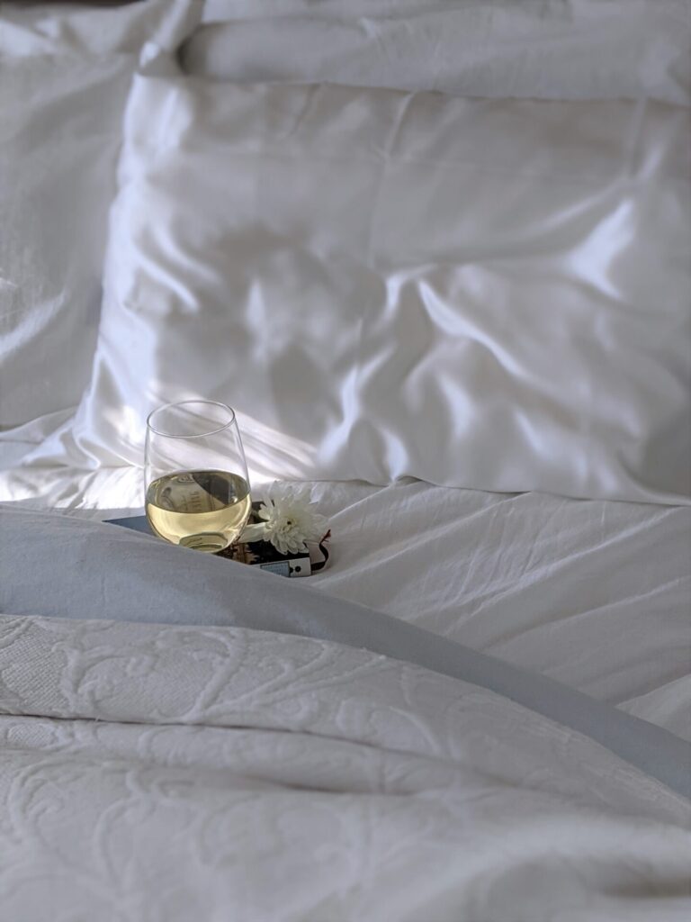 Glass of wine sat on White Bedding, if it spills they will need washing
