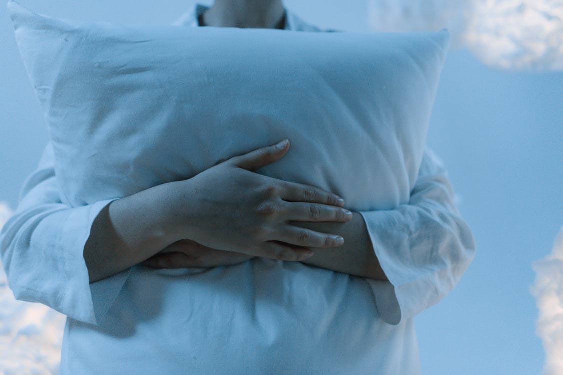 Woman clutching a pillow, Finding your best pillow is heavenly