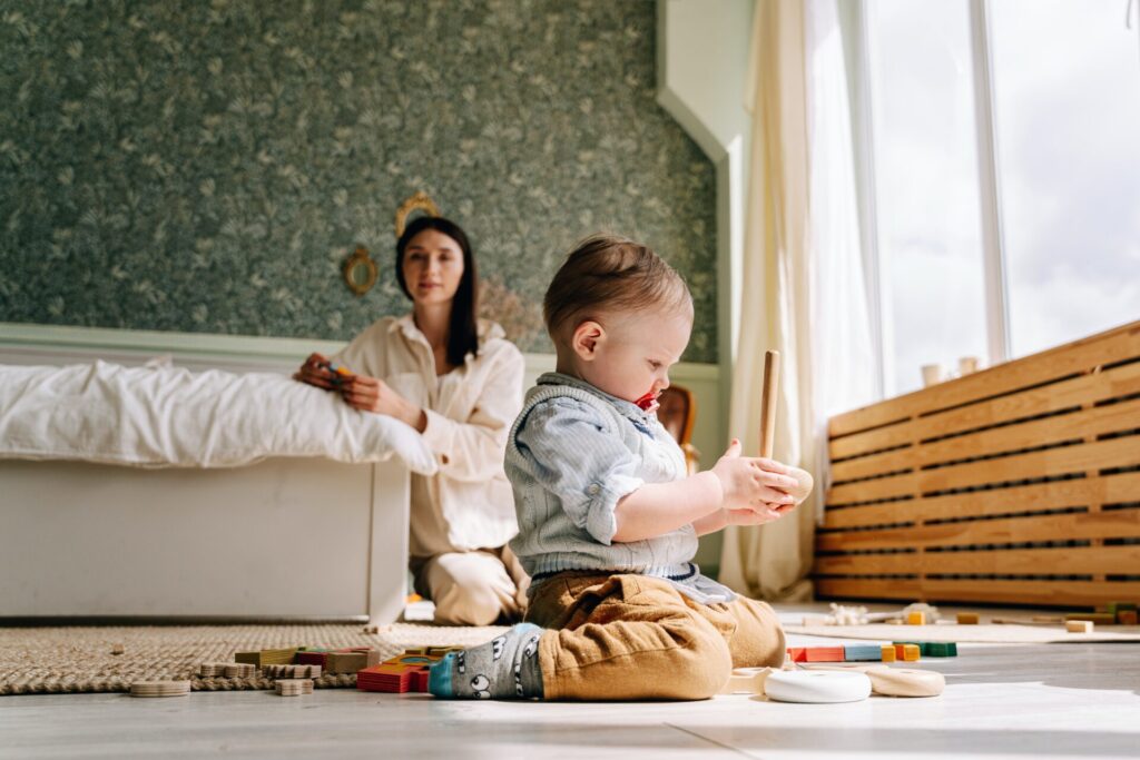 Baby playing with blocks as his mother watches. Managing your baby's sleep by tiring them out.