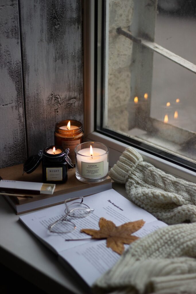 Three lit candles in the corner of a window sill 