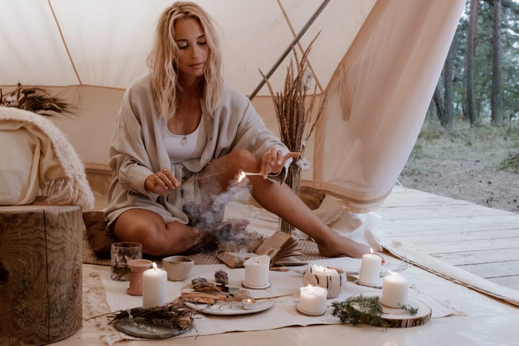 Woman in cream coloured hygge tent sat on the floor lighting candles
