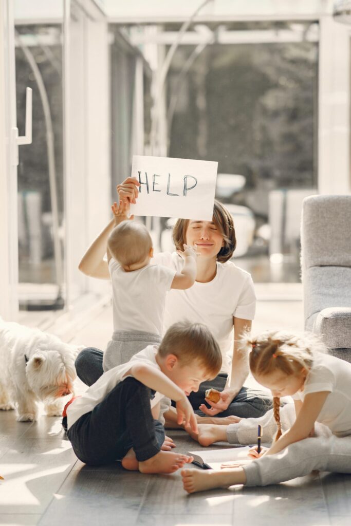 Mother surrounded by children holding up a sheet of paper that reads 'help'