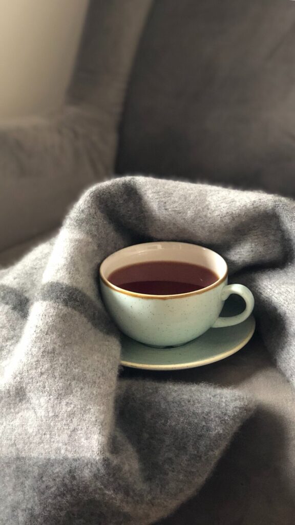 Cup of valerian tea being hugged by a blanket