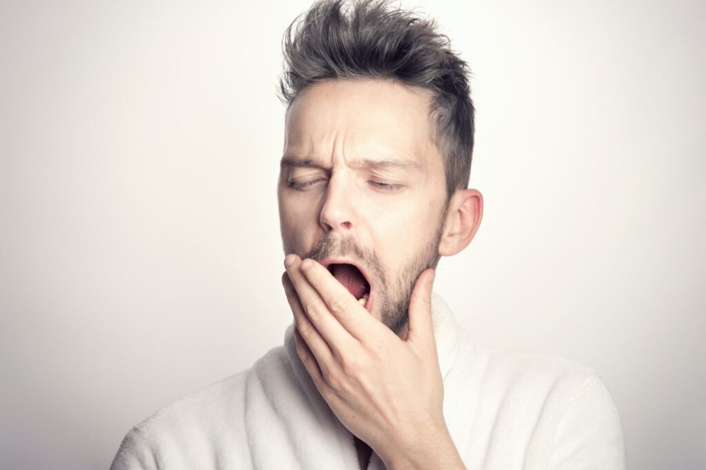 A bearded man yawning into his hand