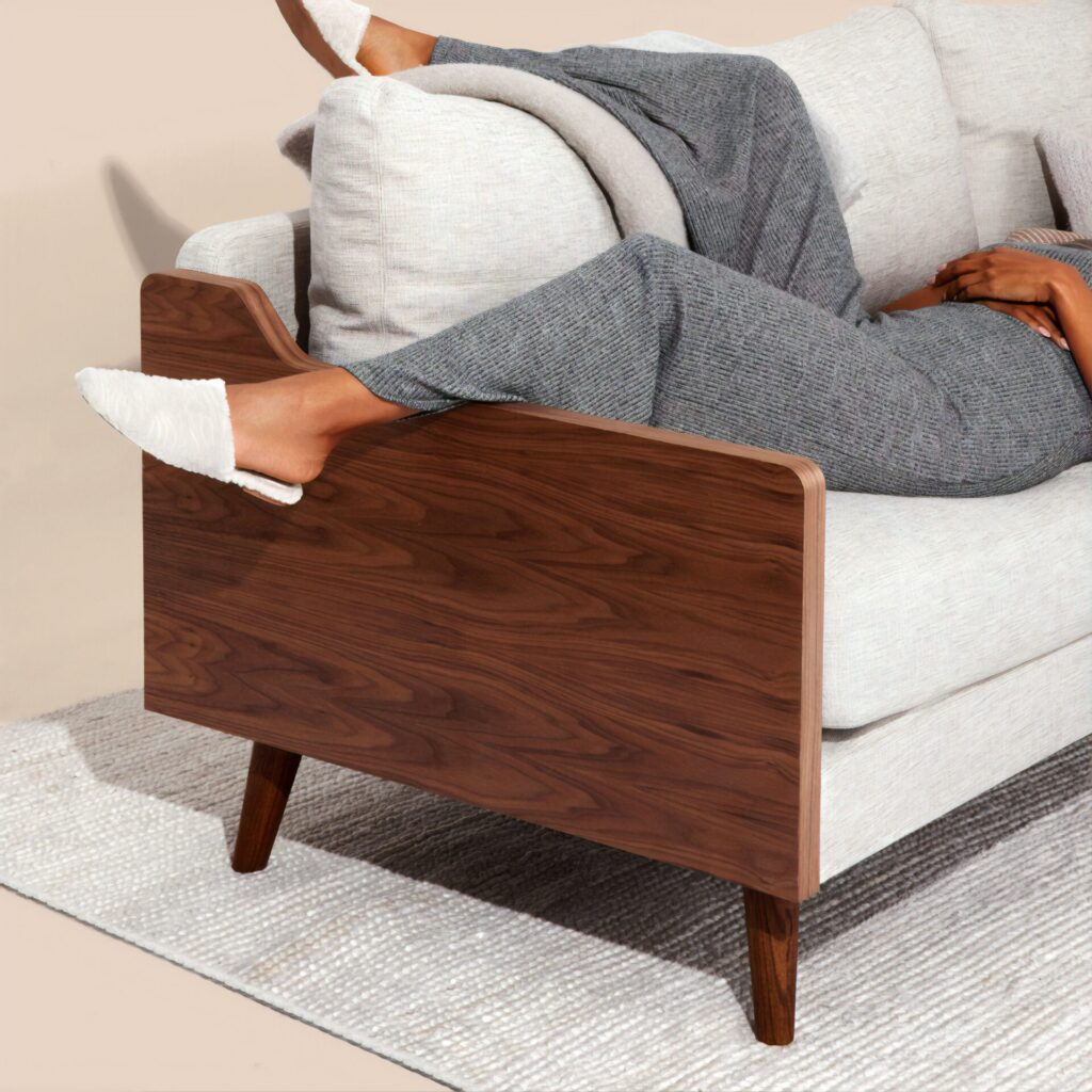Pair of legs dangling from the end of a sofa with wood panelling 