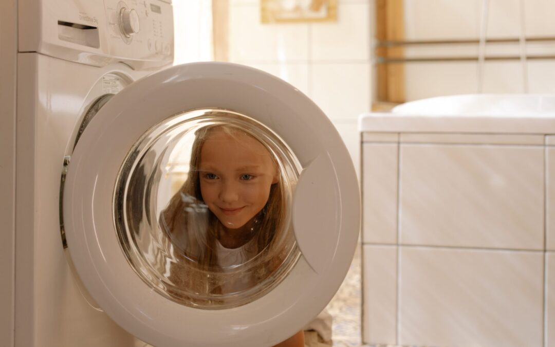Little girl peering through a washing machine window