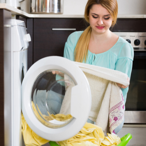 A woman taking out a waterproof mattress protector from a washing machine