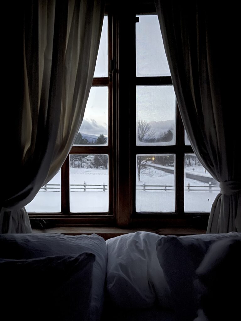 View from a bed looking out of a window onto a snowy landscape, creating a calm and cosy bedroom atmosphere