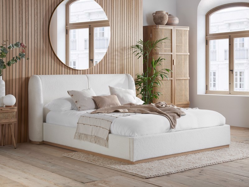 Cream upholstered ottoman storage bed with curved headboard in a modern neutral bedroom