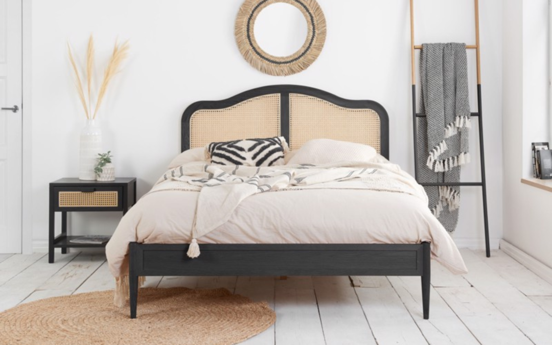 Black rattan bed frame with woven headboard in a light neutral bedroom with natural textures and soft furnishings