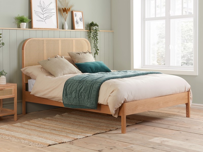 Light oak wooden bed frame with rattan headboard in a bright, minimalist bedroom with natural décor