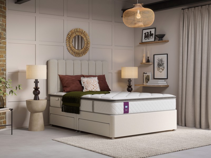 Cream divan bed with padded headboard and built-in storage drawers in a warm, contemporary bedroom setting