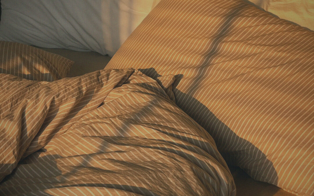 Cosy bed with striped bedding in warm morning light